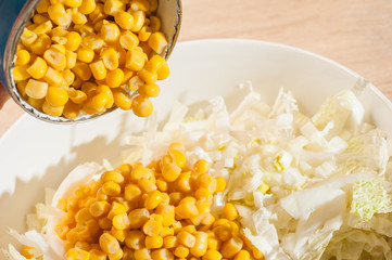 Adding canned corn to white cabbage salad