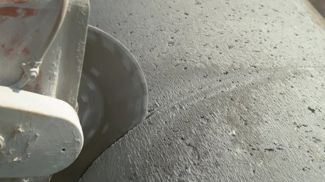 CLOSE UP: Sharp cutter blade spins before cutting into a gray concrete tube. Builder cutting into a large concrete pipe with an angular saw. Circular saw about to cut through a thick concrete pipe.