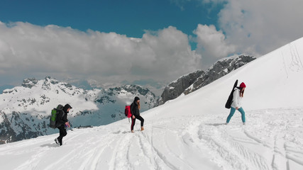 Fototapeta na wymiar Three friends walking upwards on the snow in Dolomites with big backpacks