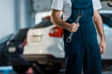 cropped view of car mechanic holding hand wrench in car service