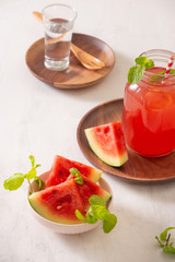 Watermelon drink in glass with slices of watermelon on whitebackground