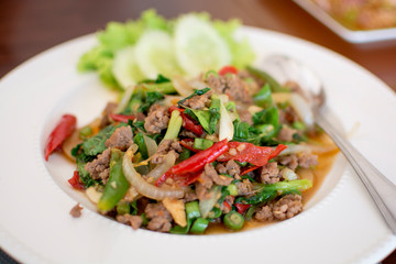 Spicy fried pork with basil leaves in white dish, Thai menu