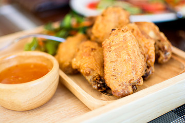 Fried crispy chicken pieces with sauce in wooden dish on table, Thailand.