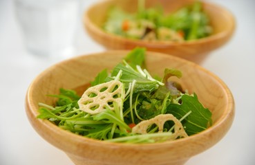 木製の食器に入った素揚げレンコンと水菜のサラダです。