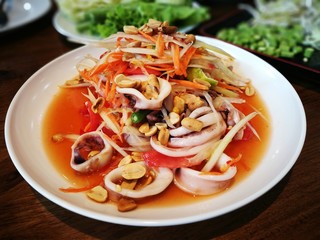 Thai style papaya salad with fresh sliced squid or Som Tam Thai recipe . The papaya salad is one of the most popular food in Thailand.  