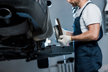 Fototapeta na wymiar cropped view of auto mechanic repairing automobile and holding car brake