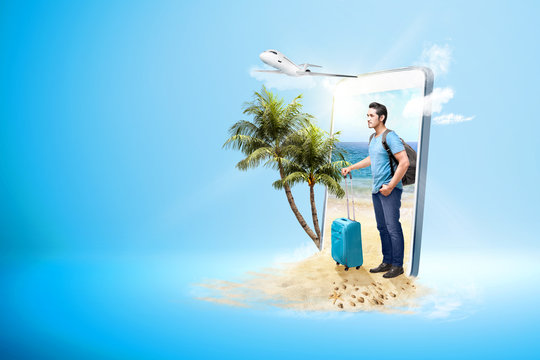 Asian man with suitcase bag and backpack standing on the beach