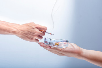 Man hand give a transparent ashtray to smoker