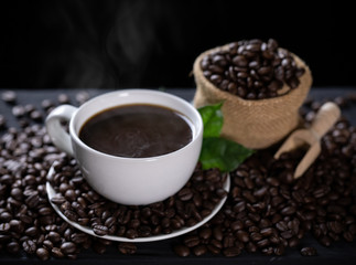 Hot coffee cup with coffee beans on the wooden table