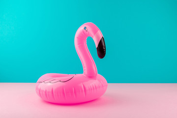 Inflatable pink flamingo on pastel blue and pink background. Pool float party, trendy summer concept. Flat lay, copy space.