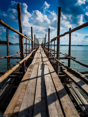 A wooden bridge with a path to the sea.