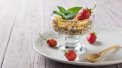 Bowl of oat flakes and strawberries on a wooden table. Food rich in fiber.