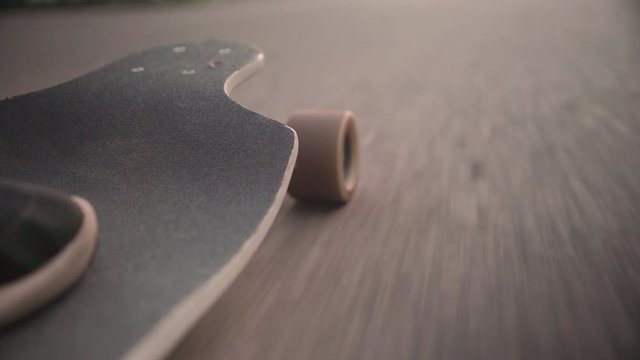 Low angle perspective of longboard riding down the road