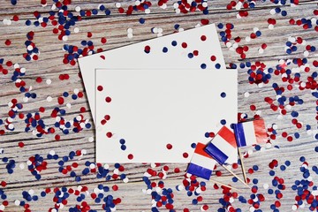 The national holiday of July 14 is a happy Independence Day of France, Bastille Day, the concept of patriotism, memory, place for text, confetti and flags on a wooden table, horizontal.