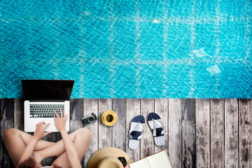 Fototapeta na wymiar Top view woman using laptop by the pool, working outdoor concept.