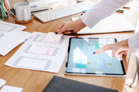 UX designer team using tablet designing smartphone prototype or application layout at office desk.