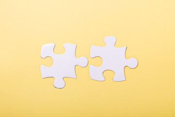 Two disconnected jigsaw puzzle pieces on yellow background White puzzle Concept success of business