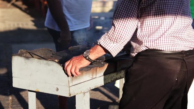 A grill chef turning the traditional Steckerlfisch on a grill.