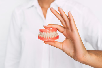 The dentist is holding dentures in his hands. Dental prosthesis in the hands of the doctor close-up. Front view of complete denture. Dentistry conceptual photo. Prosthetic dentistry. False teeth