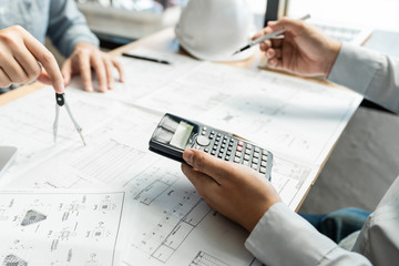 Fototapeta premium Real-estate concept, Two engineer and architect discussing blueprints data working and digital tablet on construction building project.