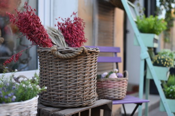 Close-up of a basket with red dried flowers on a wooden bench in front of the house