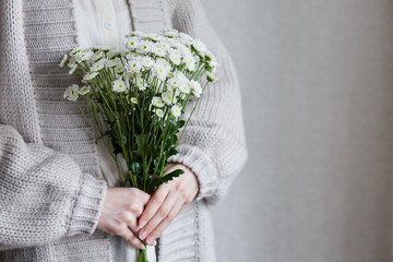 photo of young woman holding white flowers with green stem in her hands - 276647637