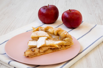 Slice of home-baked apple pie on a pink plate, side view. Close-up.