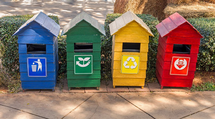 Different colored bins for collection of recycle materials on side of walkway