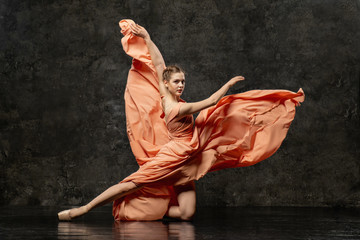 Ballerina. Een jonge balletdanser gekleed in een lange perzikjurk, spitzen met linten. Het meisje voert een elegante, sierlijke dansbeweging uit. Mooi klassiek ballet. Reclame balletschool.