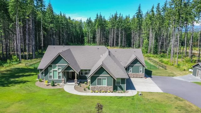 4k footage of an American suburban home surrounded by evergreen trees, aerial view with drop down approach to ground level