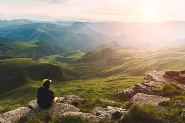 Travel man tourist sitting alone on the edge mountains over green valley adventure lifestyle extreme vacations green landscape Freedom - 276649482