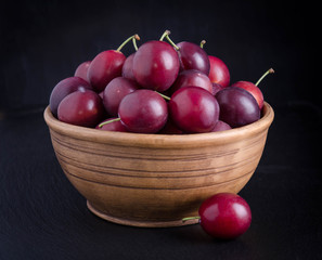 ripe plums in the bowl on black background