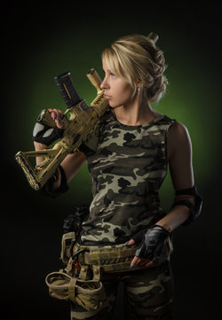 beautiful blonde girl in military clothes with a gun in her hands