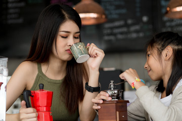 Beautiful barista teaching her sister how to make coffee.