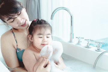 Young asian mother and daughter in a bathroom happy smiling taking bath