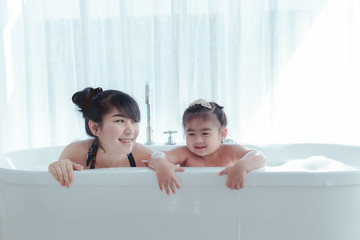 Young asian mother and daughter in a bathroom happy smiling taking bath