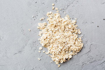 Dry raw oat flakes lying on gray concrete background. Flat grains cereals for muesli or granola. Top view. Flat lay. Overhead
