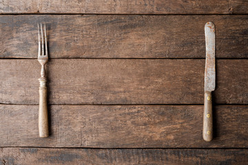 Old knife and fork on wooden table. Food background