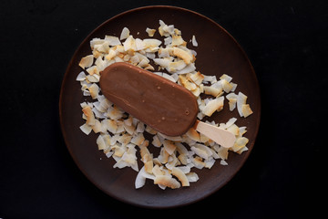 Chocolate icecream on a wooden plate with coconut shavings