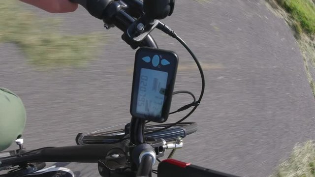 City e bike or electric bicycle  riding in the park track trail at summer. View from first person perspective POV with action camera to the electric speedometer or controller with power level. 4k.