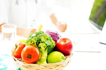 Nutritionist is advising fresh fruits and vegetables which are in the basket.