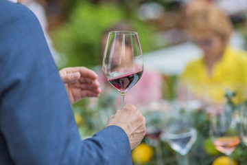 A man holds in his hands a glass of Italian or French red young wine for a tasting or a celebration of a party in honor of the wedding, birthday.