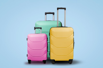 Three multi-colored plastic suitcases on wheels on a blue background. Travel concept, vacation trip, visit to relatives