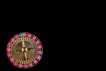Roulette table in casino, with many games and slots, roulette wheel in the foreground. Black background for text