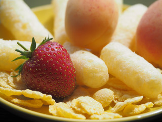 Corn sticks, cereals and fresh fruit are in the yellow plate. Perfect quick Breakfast for kids in the morning.