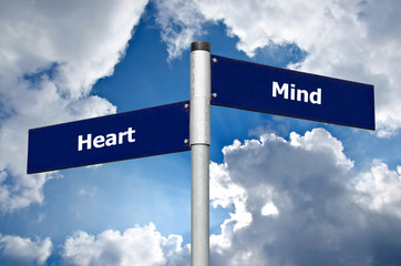Street sign in front of cloudy sky representing choice between listening to the ‘heart’ or the...