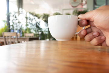 Hand holding a hot coffee cup in coffee shop