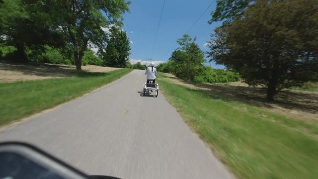 Young women riding the bike or trike, view from behind and follow POV. Women cyclist relaxing at summer ride.  Bicycle activity in Toronto, Ontario, Canada, city park. 4k.