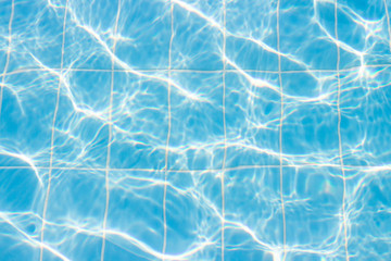 Water vibrations in the swimming pool with sun reflection. blue swimming pool surface, water background in swimming pool. Flat lay, top view