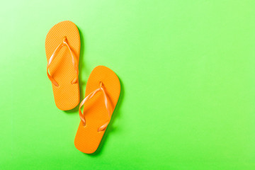 orange flip flops on green background. Top view with copy space